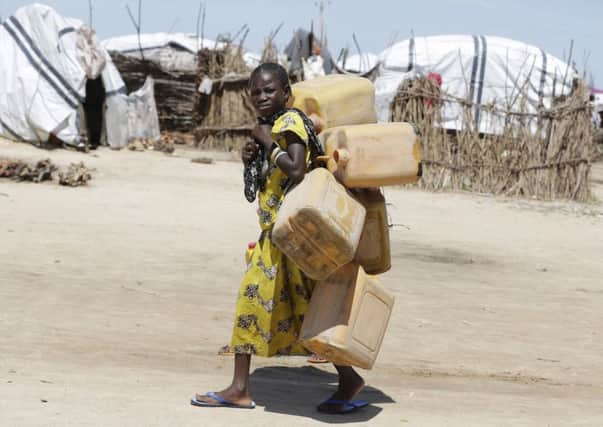A girl displaced by Islamist Extremists carries empty plastic containers at a camp Maiduguri, Nigeria.