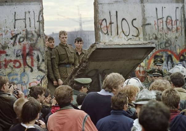 West Berliners crowd in front of the Berlin Wall in 1989 as they watch East German border guards demolish a section of the wall. Picture: AFP/Getty Images