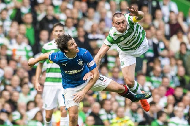 Celtic's Scott Brown takes flight in an aerial battle with Joey Barton of Rangers. Picture:  Craig Williamson/SNS