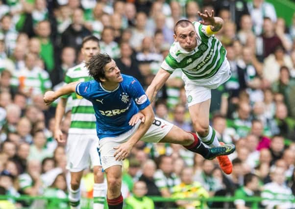 Celtic's Scott Brown takes flight in an aerial battle with Joey Barton of Rangers. Picture: Craig Williamson/SNS