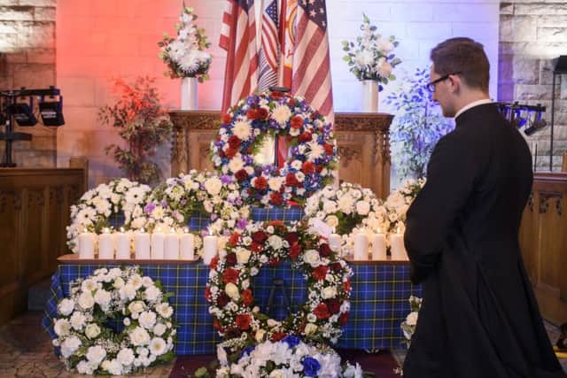 Polish Catholic Priest Maximillian MacAulay looks at the wreaths during the memorial service. Picture: PA