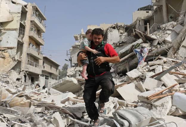 A man carries a baby after removing him from the rubble of a destroyed building in Aleppo. Picture: AFP/Getty Images