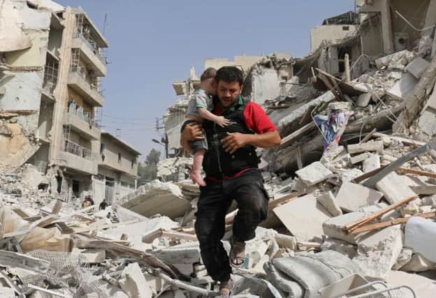 A man carries a baby after removing him from the rubble of a destroyed building in Aleppo. Picture: AFP/Getty Images