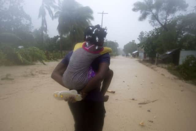A woman and a child walk in a waterlogged street as they head to a shelter under the pouring rain caused by Hurricane Matthew, in Leogane, Haiti. Picture: AP