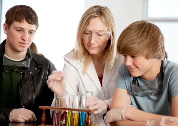 A head and shoulders image of a teacher teaching high school students about chemistry in science class.