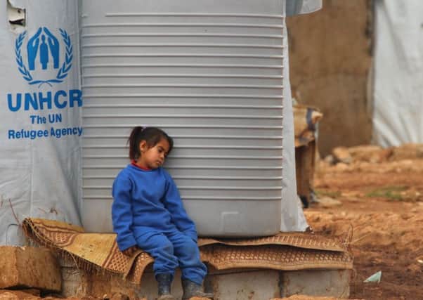 A Syrian girl rests by a water tank at a refugee camp in Baalbek. Picture: Getty