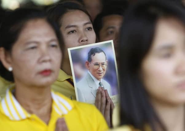 Thais pray as they hold a picture of King Bhumibol Adulyadej, whose health is deteriorating. Picture: AP