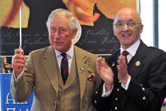 Prince Charles cuts a cake to mark the 125th anniversary of An Comunn Gaidhealach, with An Comunn president John Macleod.