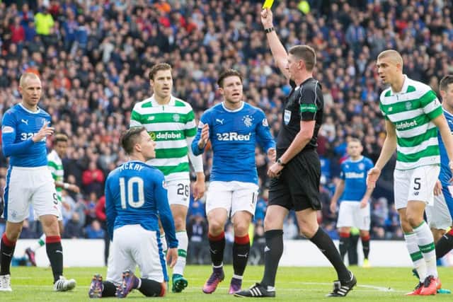 Craig Thomson shows a yellow card to Barrie McKay after believing the Rangers winger to have dived for a penalty. Picture: PA