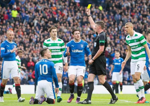Craig Thomson shows a yellow card to Barrie McKay after believing the Rangers winger to have dived for a penalty. Picture: PA