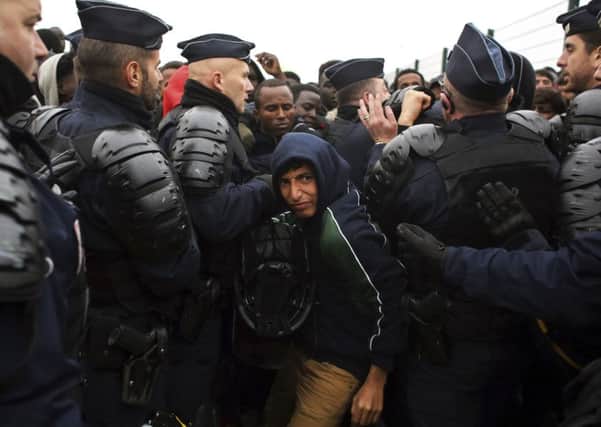 A migrant makes his way through a police cordon in the makeshift migrant camp known as "the jungle" near Calais, as French authorities begin to shut it down. Picture: AP Photo/Thibault Camus