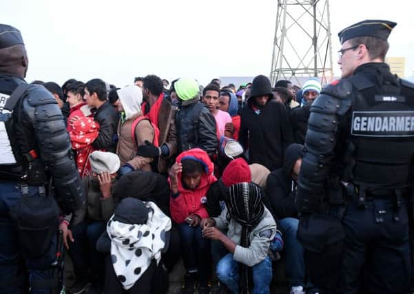 French anti-riot policemen stand guard a gathering of migrants during the full evacuation of the Calais "Jungle" camp, in Calais, northern France,Picture: / AFP PHOTO / FRANCOIS LO PRESTIFRANCOIS LO PRESTI/AFP/Getty Images