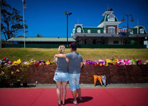 Wayne Marmo hugs his daughter Emily as they lay flowers at a makeshift floral tribute at the Dreamworld theme park on the Gold Coast. AFP PHOTO / Patrick HAMILTONPATRICK HAMILTON/AFP/Getty Images