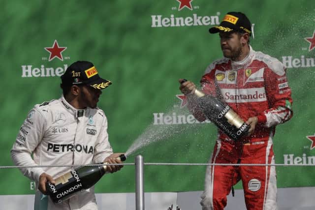 Mexican Grand Prix winner Lewis Hamilton, left, of Mercedes celebrate on the podium with Ferrari's Sebastian Vettel, who was third but later stripped of his podium place. Picture: Rebecca Blackwell/AP