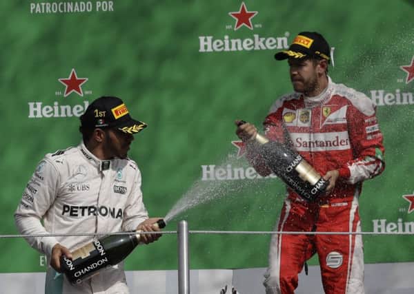 Mexican Grand Prix winner Lewis Hamilton, left, of Mercedes celebrate on the podium with Ferrari's Sebastian Vettel, who was third but later stripped of his podium place. Picture: Rebecca Blackwell/AP