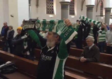 Fans hold their scarves aloft as the choir sings. Picture: PA