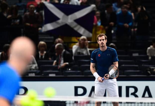 A fan holds a Scottish flag high as Andy Murray hits balls with coach Jamie Delgado after his opponent Milos Raonic withdrew from their semi-final and he became World No.1. Picture: Getty Images
