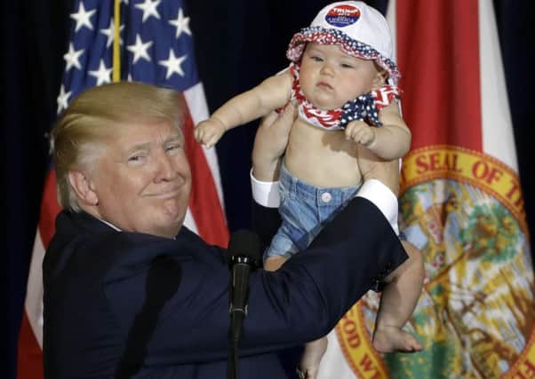 Trump holds up a baby at a campaign rally in Tampa, Florida, yesterday. Picture: Chris O'Meara/AP