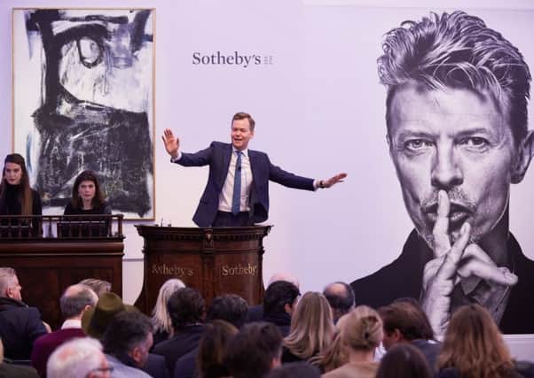 Auctioneer Oliver Barker fields bids at the sale of David Bowies personal art collection. Picture: Getty Images
