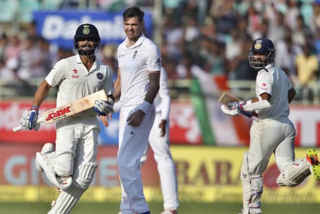 England's James Anderson, centre, watches India captain Virat Kohli, left, and Ajinkya Rahane run between the wickets. Picture: Aijaz Rahi/AP