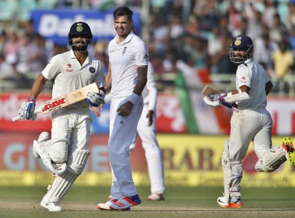 England's James Anderson, centre, watches India captain Virat Kohli, left, and Ajinkya Rahane run between the wickets. Picture: Aijaz Rahi/AP