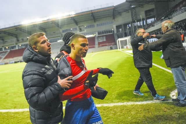 Jordan Larsson, centre, son of former Celtic star Henrik Larsson, is escorted from the pitch after being confronted by fans. Picture: AP