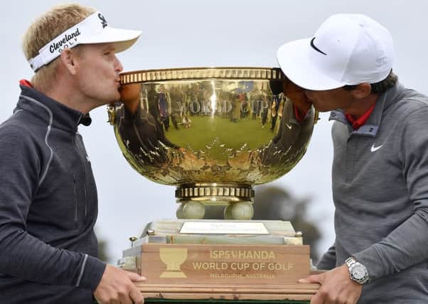 Denmark's Soren Kjeldsen, left, and partner Thorbjorn Olesen kiss the trophy after winning the World Cup of Golf at Kingston Heath in Melbourne. Picture: AP Photo/Andrew Brownbill