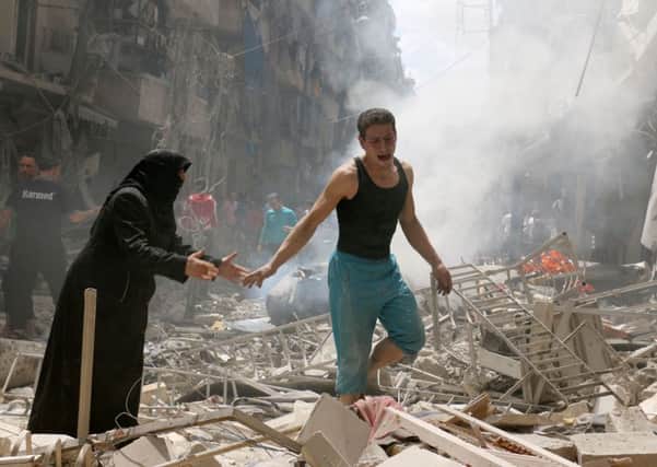 People walk amid the rubble of destroyed buildings following a reported air strike on the rebel-held neighbourhood of al-Kalasa in the northern Syrian city of Aleppo. Picture: Getty Images