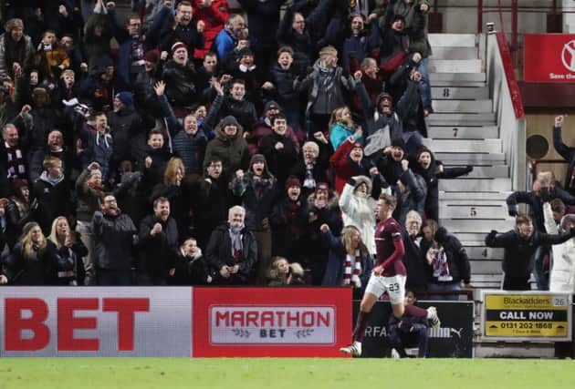 Robbie Muirhead scores his second goal in front of a joyous Hearts support. Picture: PA