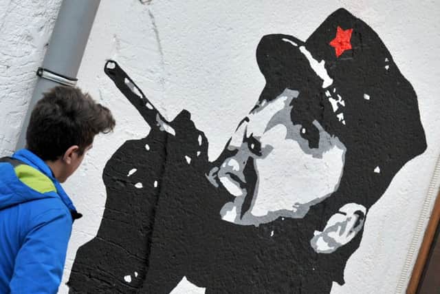 A pedestrian walks past a mural depicting Cuban revolutionary leader Fidel Castro in Montenegro. Picture: AFP