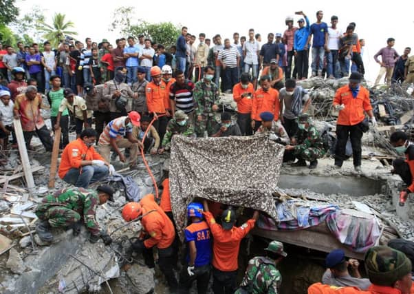 Indonesian soldiers and a search and rescue team look for survivors amongst the rubble yesterday in Lueng Putu town, Aceh province. Picture: Getty Images