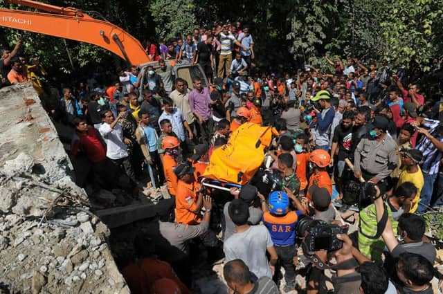 Indonesian search and rescue personnel retrieve a body from the rubble of a collapsed building following an earthquake in Pidie, Aceh province. Picture: AFP/Getty Images