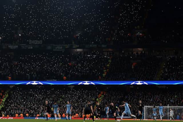 Celtic fans hold aloft their illuminated phones to light the stand during the Champions League clash with Manchester City. Picture: AFP/Getty