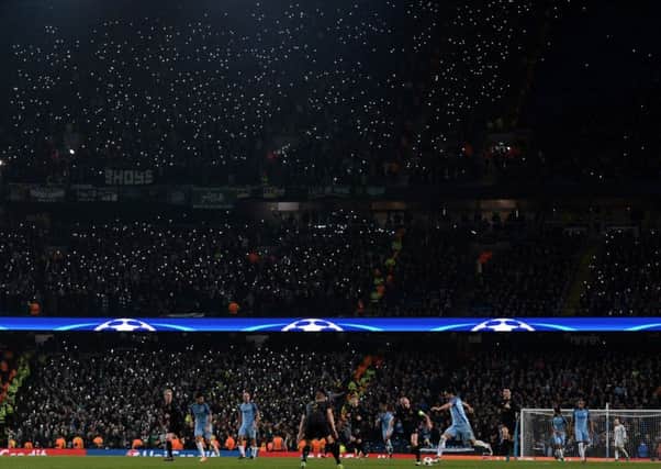 Celtic fans hold aloft their illuminated phones to light the stand during the Champions League clash with Manchester City. Picture: AFP/Getty