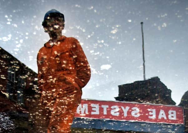 A worker, reflected in a puddle, leaves the BAE Systems yard in Govan. Picture: PA