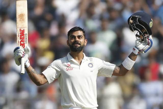 India captain Virat Kohli raises his bat and helmet after scoring a double century against England. Picture: Rafiq Maqbool/AP