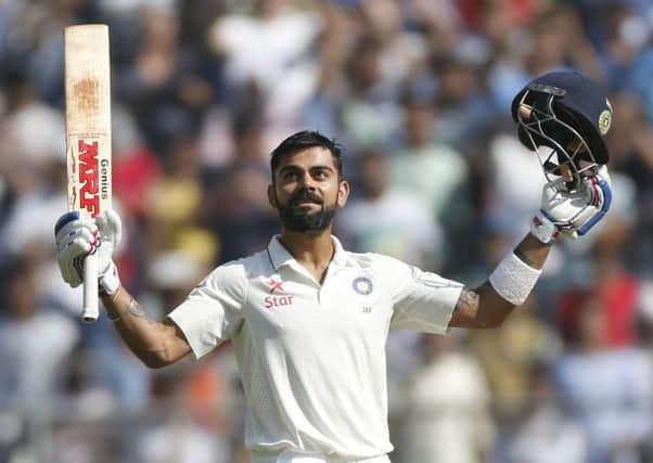 India captain Virat Kohli raises his bat and helmet after scoring a double century against England. Picture: Rafiq Maqbool/AP