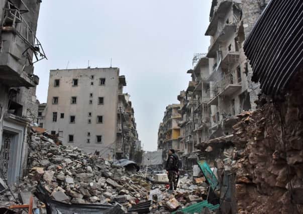 A member of the Syrian government forces stands in a severely damaged street in Aleppo's newly captured Al-Kalasseh neighbourhood.

 Picture:  AFP/Getty Images