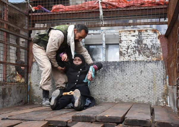 A woman is helped on to the back of a truck after being injured in an airstrike