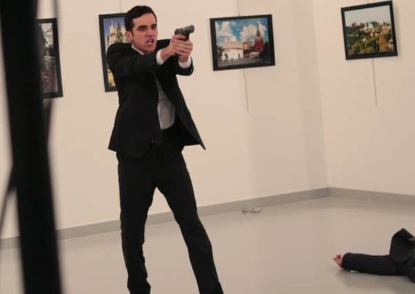An unnamed gunman gestures after shooting Andrei Karlov, the Russian Ambassador to Turkey, at a photo gallery in Ankara. AP Photo/Burhan Ozbilici