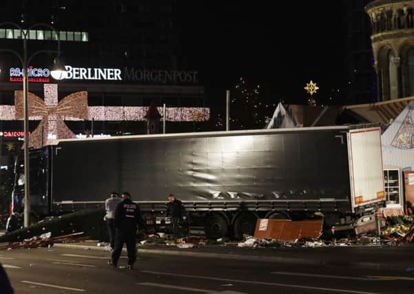 Police officers stand beside the truck which ran into a crowded Christmas market and killed 12 people in Berlin, Germany. (AP Photo/Michael Sohn)