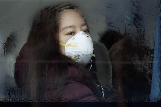 A woman wearing a mask for protection against air pollution looks out from a bus in Beijing. Picture: AP Photo/Andy Wong