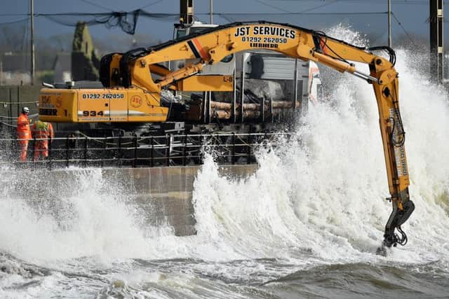 Workmen place large rocks in the sea to bolster flood defences along the sea wall.  (Photo by Jeff J Mitchell/Getty Images)