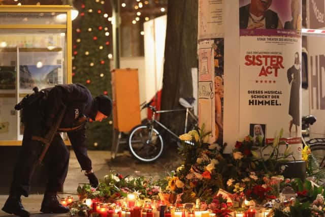 A policeman places a candle on behalf of a mourner at a makeshift memorial in Berlin.  (Photo by Sean Gallup/Getty Images)