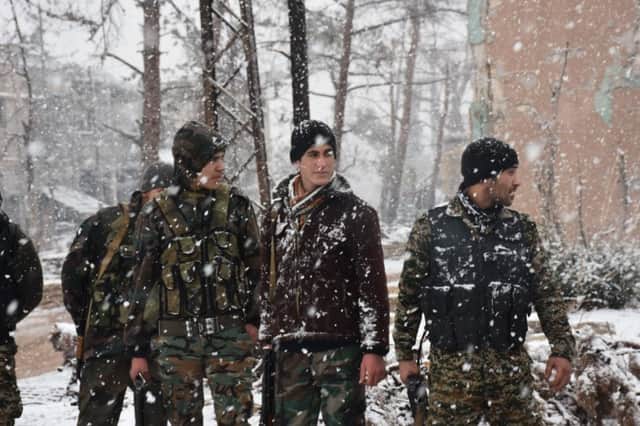 Syrian pro-government forces walk as snow falls in Aleppo. Picture: AFP/George Ourfalian/Getty Images