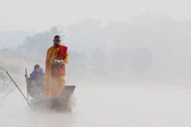 Winner - Buddhist monk going to collect food from a village  in a boat on the Rangkong River, Bangladesh by Jewel Chakma. Picture: SWNS