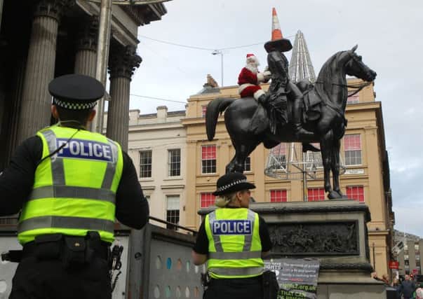 Protester Ricky McConnell, dressed up as Santa, sits on top of the Duke of Wellington statue in Glasgow city centre.