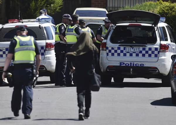 Police accompany a woman as they attend the scene where a house was raided at Meadow Heights in Melbourne, Australia, (Julian Smith/AAP Image via AP)