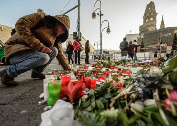 A mourner places a candle at a makeshift memorial near the site where a truck crashed into a Christmas market. Picture: AFP/Getty Images