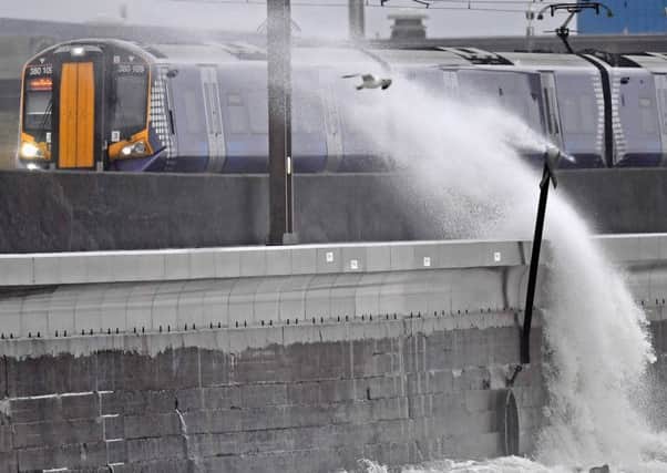 A Scotrail train passes as waves crash against the new weather defences at Saltcoats railway station. Picture: Getty Images